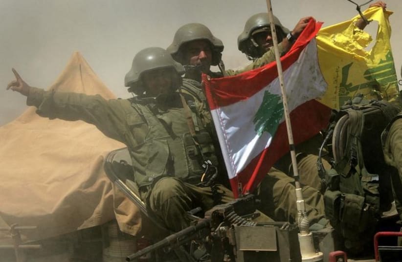 An Israeli armored personnel carrier team shows a Hezbollah and Lebanese flag as they return from fighting near the Israeli village of Avivim, July 25, 2006 (photo credit: REUTERS)