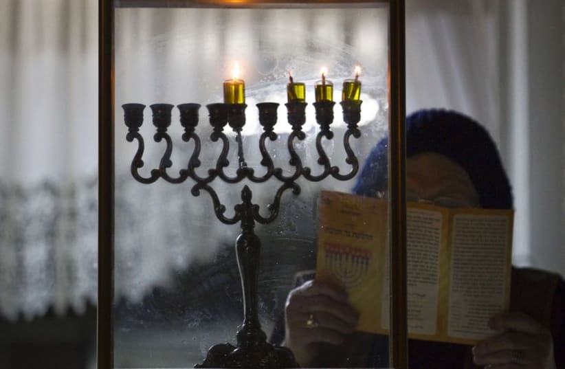 An ultra-Orthodox Jewish woman prays after lighting candles on the third night of the holiday of Hanukkah in the southern city of Ashdod (photo credit: REUTERS)