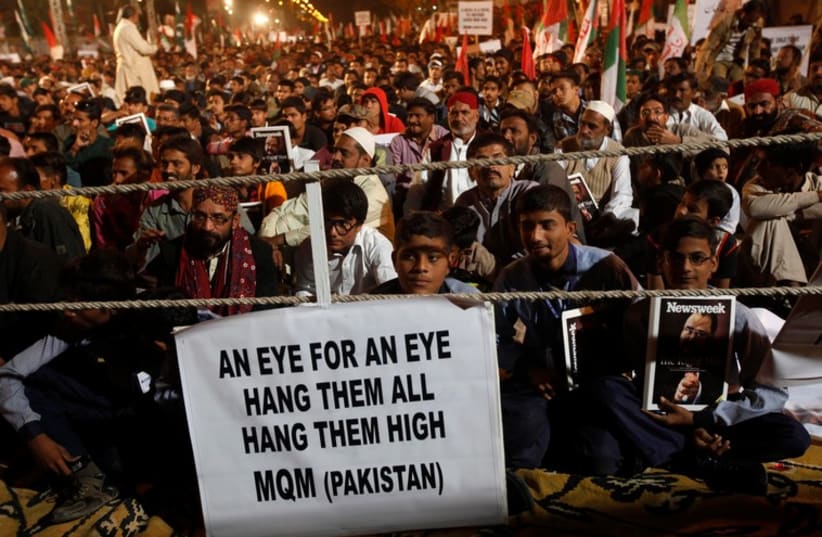 Supporters of Pakistan's Muttahida Quami Movement (MQM) political party hold a sign to condemn the Taliban attack on the Army Public School in Peshawar (photo credit: REUTERS)