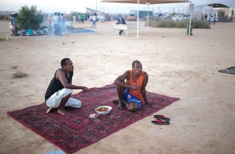 Migrants eat dinner outside the Holot open detention facility. (photo credit: REUTERS)
