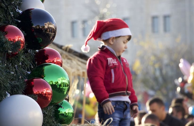  A young boy stands by the main Christmas tree in Manger square, Bethlehem (photo credit: DOV LIEBER)