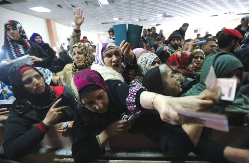 WOMEN PRESENT their passports as they ask for permits to cross from Gaza into Egypt (photo credit: REUTERS)