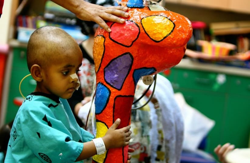 Orel, a 5 year old cancer patient, sits on his intravenous drip stand decorated with an animal figure at Schneider Children's Medical Center. (photo credit: REUTERS)