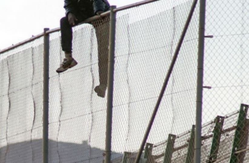 A MAN sits on a fence in Melilla, a Spanish enclave in North Africa. Those successfully scaling the fence are entitled to apply for asylum. (photo credit: REUTERS)