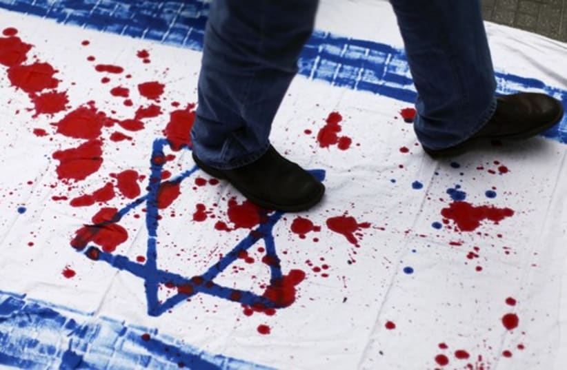 A Venezuelan student walks over a cloth with red paint and the Star of David during an anti-Israel demonstration in Caracas. (photo credit: REUTERS)
