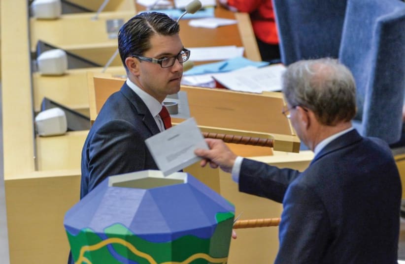 The leader of the Sweden Democrats Jimmie Akesson hands over his ballot to parliament speaker Per Westerberg during voting for the second deputy speaker in the Swedish parliament, in Stockholm in September. (photo credit: REUTERS)