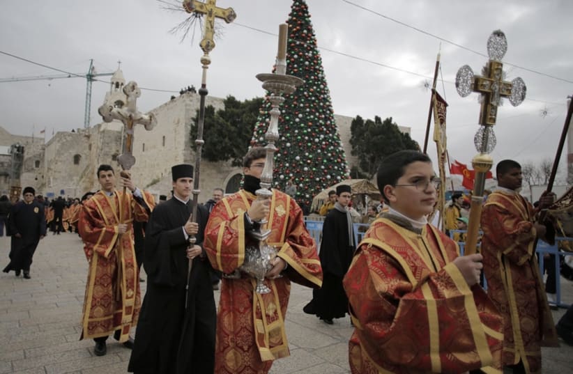 Members of the Greek Orthodox clergy wait for the arrival of the Greek Patriarch of Jerusalem Metropolitan Theophilos before the Eastern Orthodox Christmas procession outside the Church of the Nativity in the West Bank town of Bethlehem (photo credit: REUTERS)