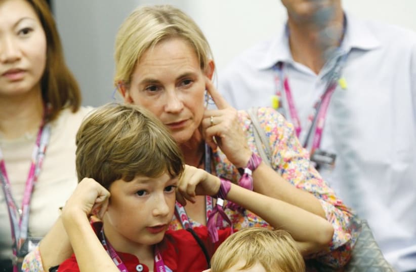 A mother and her children cover their ears at a Formula 1 race (illustrative). (photo credit: REUTERS)