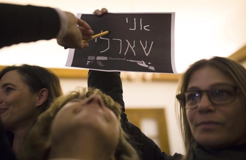 A woman holds a placard that reads "I Am Charlie" in Hebrew during a memorial service at the residence of France's ambassador to Israel in Jaffa (photo credit: REUTERS)