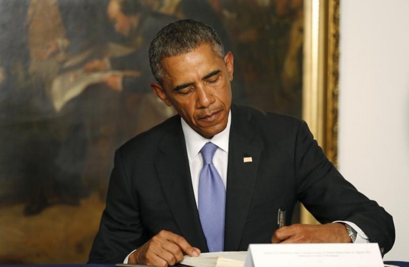 US President Barack Obama signs a condolences book as he pays his respects for victims of the attack at the French newspaper Charlie Hebdo (photo credit: REUTERS)