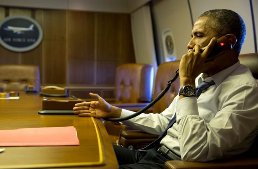 President Barack Obama talks on the phone with French President Francois Hollande from aboard Air Force One, Jan. 7, 2015. (photo credit: OFFICIAL WHITE HOUSE PHOTO / PETE SOUZA)