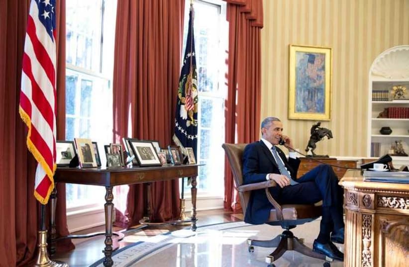US President Barack Obama talks on the phone in the Oval Office in this December 17, 2014 White House handout photo (photo credit: REUTERS)