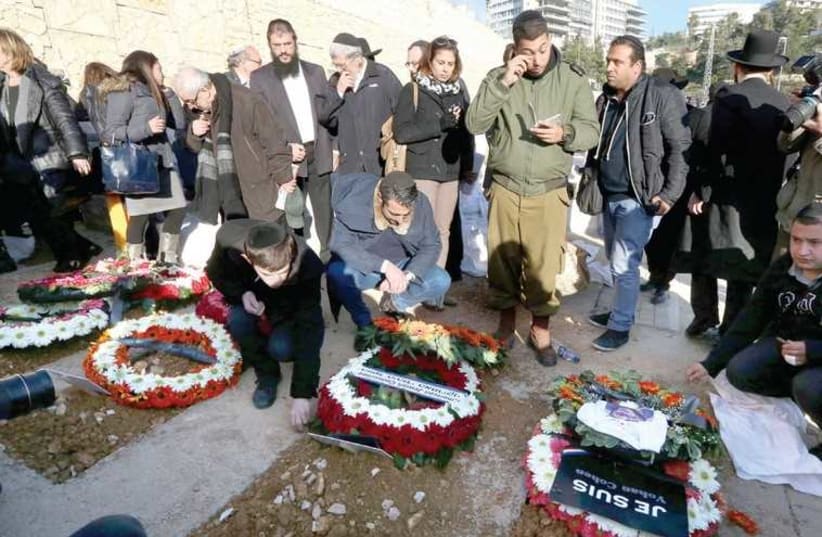 MOURNERS PAY THEIR RESPECTS at the capital’s Har Hamenuhot cemetery yesterday at the graves of the victims of the Paris Hyper Cacher terrorist attack. (photo credit: MARC ISRAEL SELLEM/THE JERUSALEM POST)