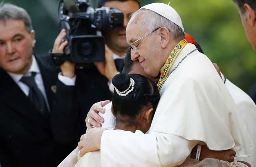 Pope Francis embraces a boy and a girl during a meeting with young people at Manila university (photo credit: REUTERS)