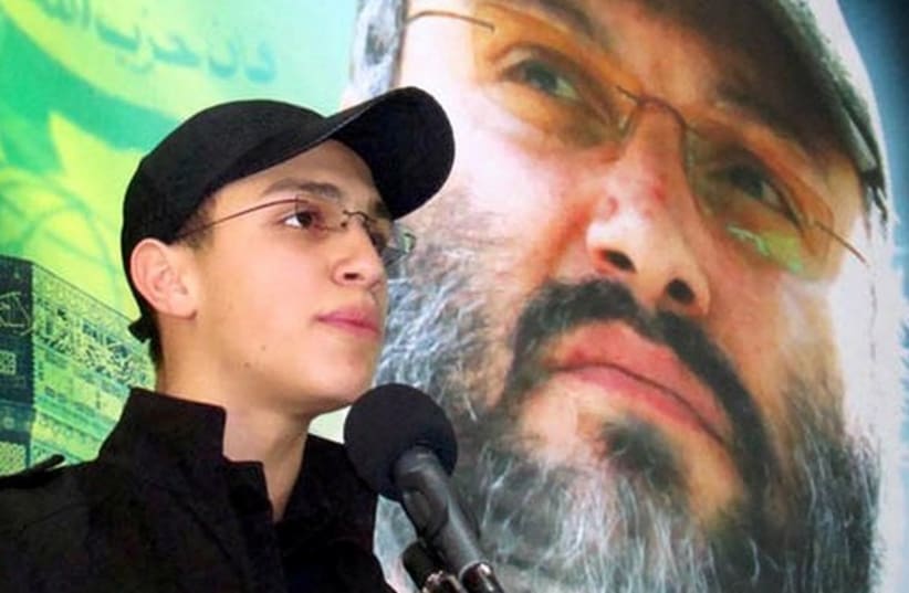 Jihad Mughniyeh stands in front of photo of his slain father, Hezbollah commander Imad Mughniyeh (photo credit: ARAB MEDIA)