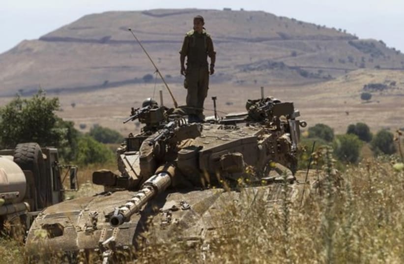An IDF soldier stands atop a tank near Alonei Habashan on the Golan Heights, close to the ceasefire line between Israel and Syria (photo credit: REUTERS)