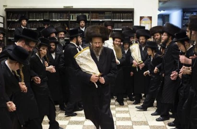 Ultra-Orthodox Jews dance with Torah scrolls during the celebrations of Simchat Torah in a synagogue in the Mea Shearim neighborhood of Jerusalem (photo credit: REUTERS)