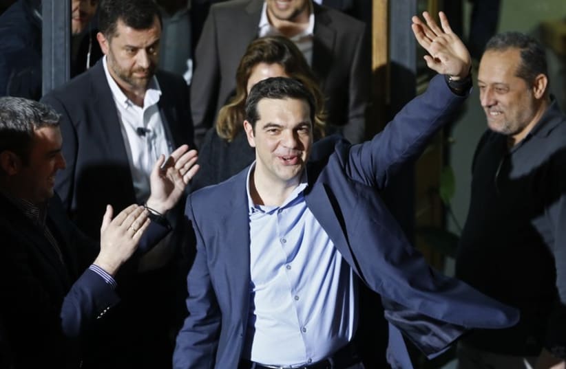 The head of radical leftist Syriza coalition, Alexis Tsipras, waves while leaving the party headquarters after winning the elections in Athens‏. (photo credit: REUTERS)