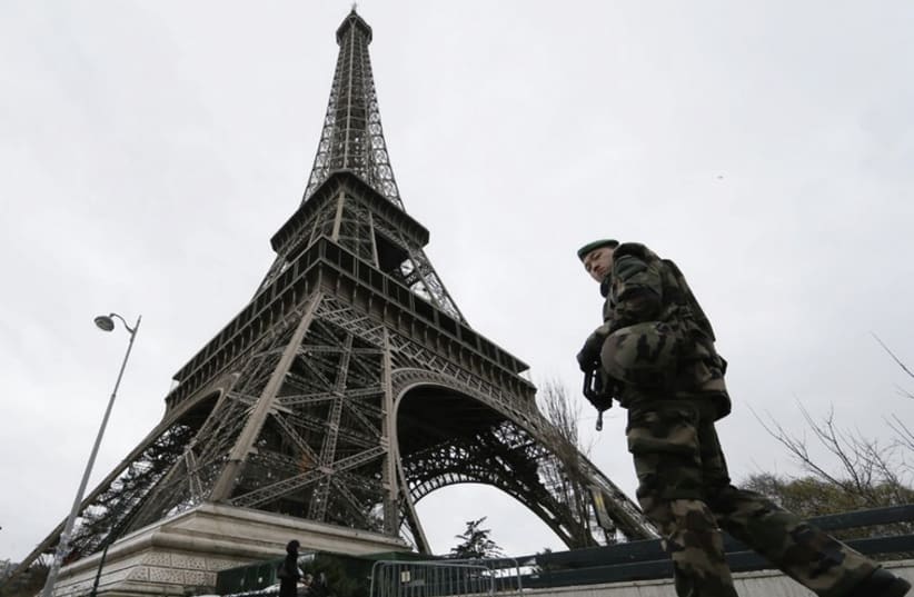 A soldier patrols alongside the Eiffel Tower. (photo credit: GONZALO FUENTES / REUTERS)