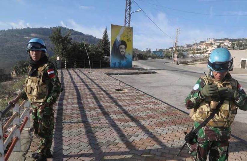UNIFIL members beside a banner for Hezbollah leader Sayyed Hassan Nasrallah in south Lebanon  (photo credit: REUTERS)