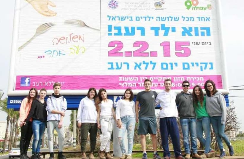 WIZO students stand under billboard in Afula for Day without Hunger (photo credit: Courtesy)