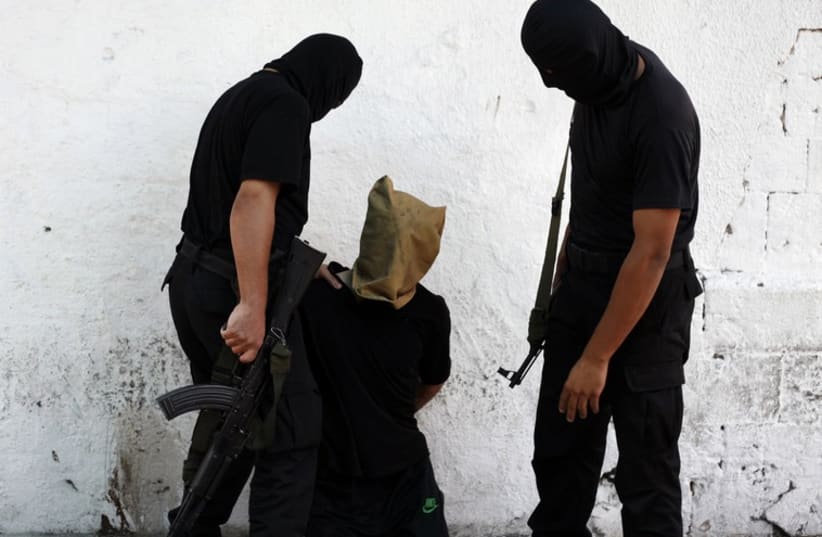 A Hamas militant grabs a Palestinian suspected of collaborating with Israel, before being executed in Gaza City August 22, 2014. (photo credit: REUTERS)