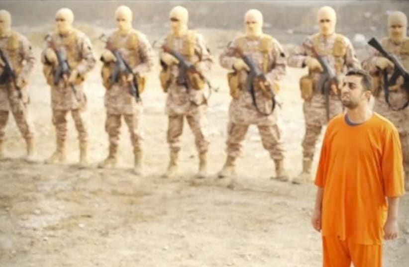 A man purported to be Islamic State captive Jordanian pilot Muath al-Kasaesbeh (in orange jumpsuit) stands in front of armed men (photo credit: REUTERS)