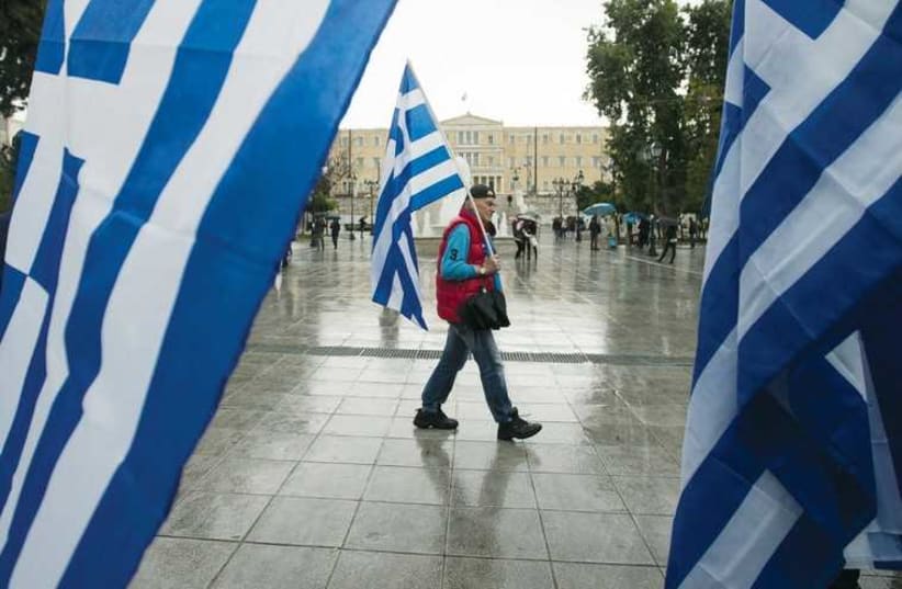 A man holding a Greek flag walks on central Syntagma square in Athens. (photo credit: REUTERS)