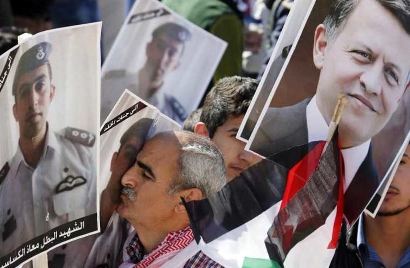 A Jordanian protester kisses a poster bearing the image of Jordanian pilot Muath al-Kasaesbeh during a rally to show their loyalty to King Abdullah (photo credit: REUTERS)