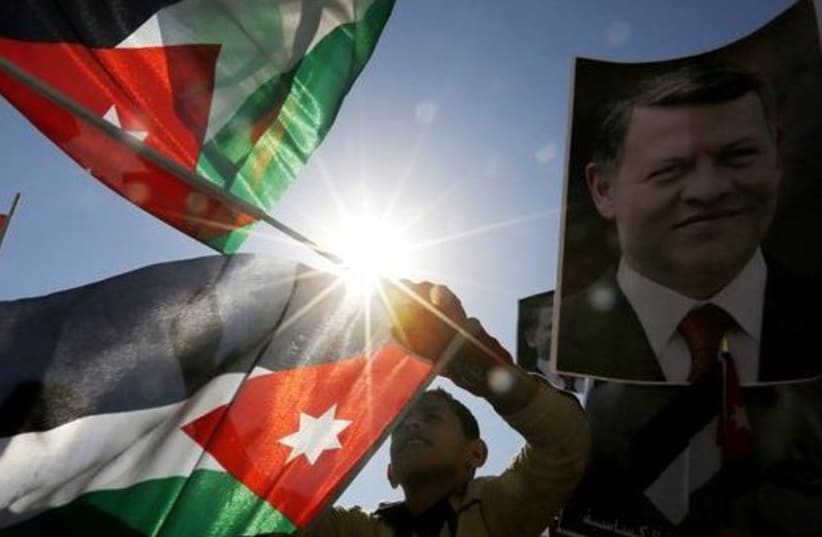 Protesters hold up pictures of Jordanian King Abdullah and pilot Muath al-Kasaesbeh with national flags (photo credit: REUTERS)