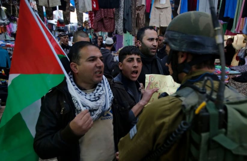 Palestinian protesters argue with an IDF soldier during a protest against the visit of President Reuven Rivlin to Hebron (photo credit: REUTERS)