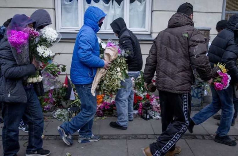 People who knew the gunman remove flowers laid at the place where he was killed by police. (photo credit: REUTERS)