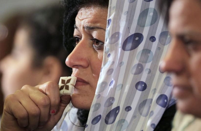 A Coptic Christian attends the Coptic mass prayers for the Egyptians beheaded in Libya, at Saint Mark's Coptic Orthodox Cathedral in Cairo. (photo credit: REUTERS)