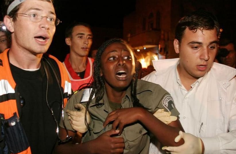 An Israeli Border Policewoman is helped by rescuers after she was injured in a suicide bombing (photo credit: REUTERS)