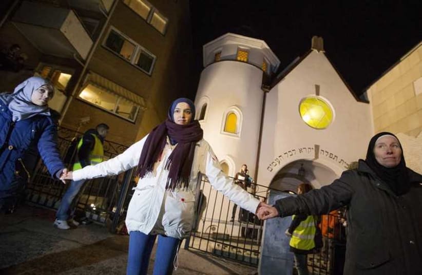 Muslim women join hands to form a human shield as they stand outside a synagogue in Oslo February 21, 2015. More than 1000 Muslims formed a human shield around Oslo's synagogue on Saturday. (photo credit: REUTERS)