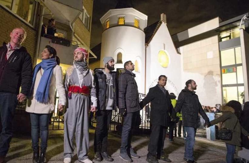 Muslims join hands to form a human shield as they stand outside a synagogue in Oslo (photo credit: REUTERS)