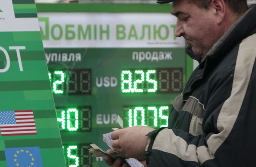 Man counts money near currency exchange in Kiev [file] (photo credit: REUTERS)