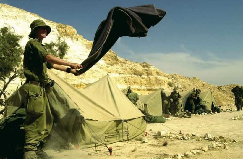 A female IDF soldier shaking out a blanket during a week-long survival course for women in the infantry at an undisclosed location in Israel (photo credit: REUTERS)