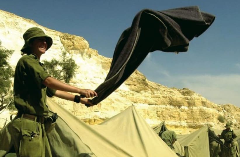 A female IDF soldier shaking out a blanket during a week-long survival course for women in the infantry at an undisclosed location in Israel (photo credit: REUTERS)