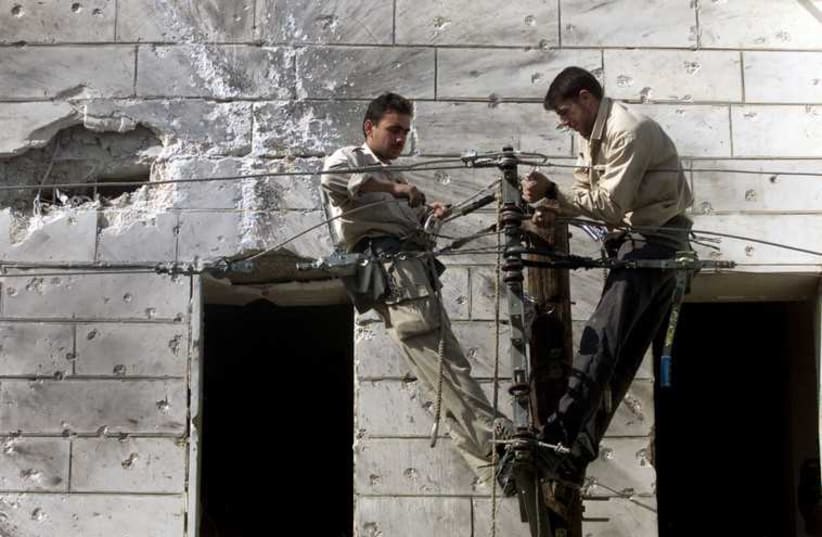Palestinian electricians repair electric cables. (photo credit: REUTERS)