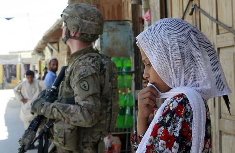A girl stands next to a US in Jalalabad, Afghanistan (photo credit: REUTERS)