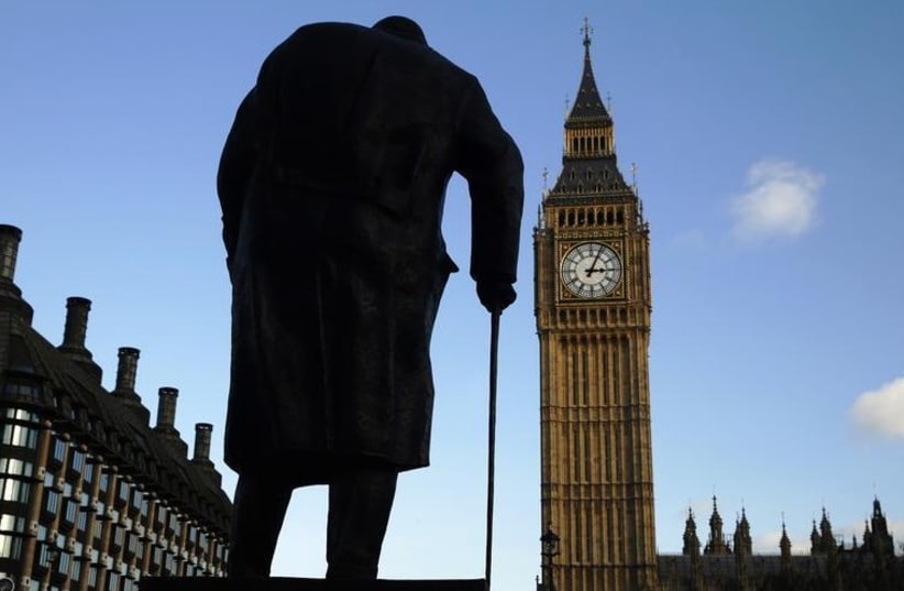 The statue of Britain's former Prime Minister Winston Churchill is silhouetted in front of the Houses of Parliament in London (photo credit: REUTERS)