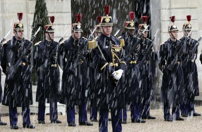 Snowflakes fall as Republican Guards stand in formation in the courtyard of the Elysee Palace (photo credit: REUTERS)