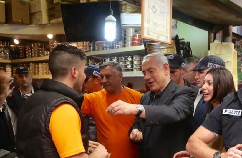 Prime Minister Benjamin Netanyahu making a purchase during his surprise visit to Mahane Yehuda market on March 9, 2015 (photo credit: MARC ISRAEL SELLEM/THE JERUSALEM POST)