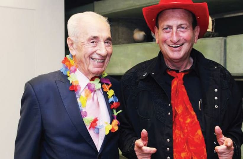 TWO-GUN HULDAI (right) and a ‘lei-d back’ Shimon Peres at the Purim party they co-hosted.  (photo credit: SALI BEN-ARIEH)
