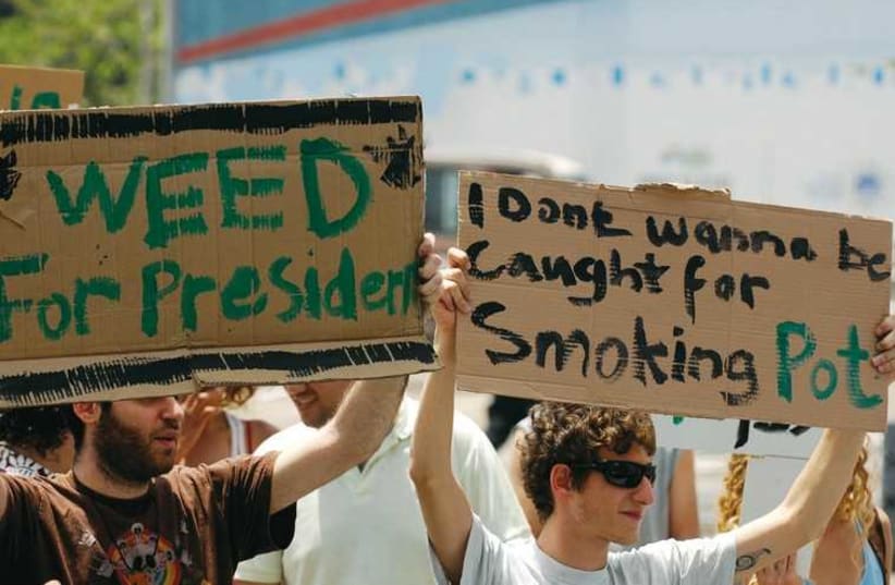 Demonstrators hold signs at a 2010 rally in Tel Aviv for the legalization of marijuana. (photo credit: REUTERS)