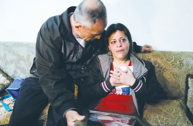 THE PARENTS of Israeli teen Muhammad Said Musallam, whom a child purportedly shot dead in an Islamic State video, react on Tuesday as they hold pictures of him in their Jerusalem home. (photo credit: REUTERS)