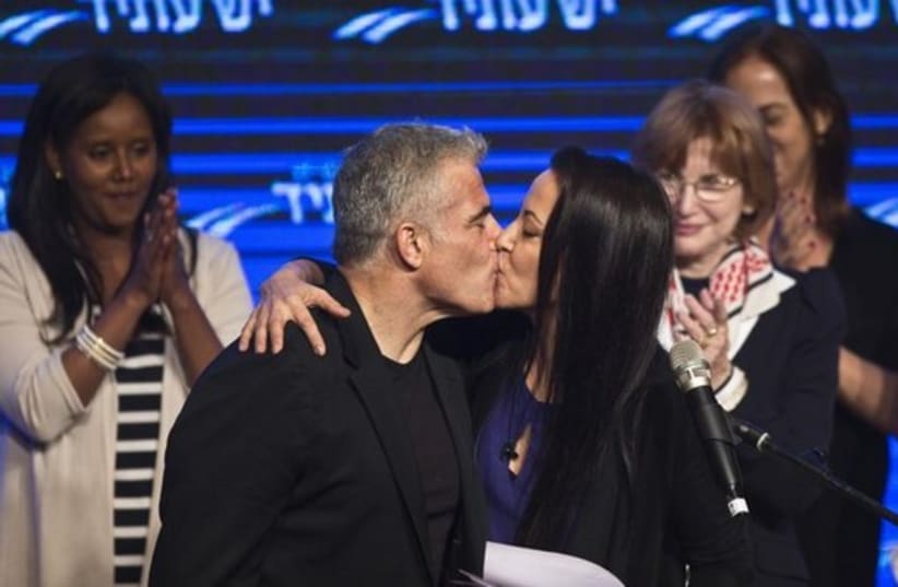 Yesh Atid leader Yair Lapid and his wife Lihi kiss at a women's committee convention in Tel Aviv (photo credit: REUTERS)