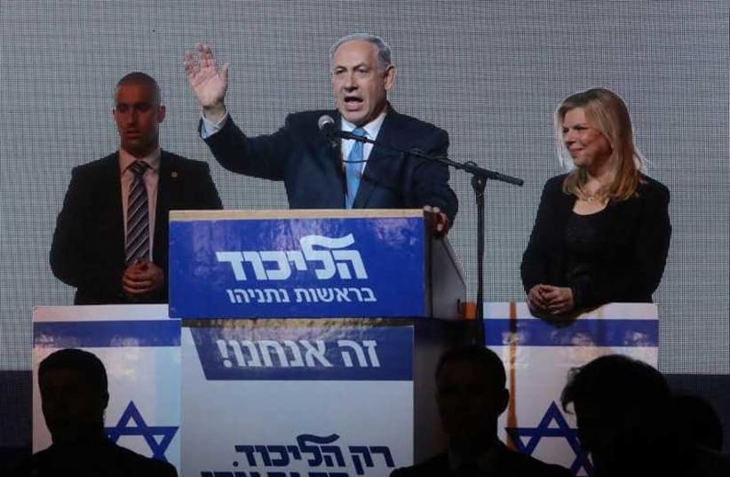 Prime Minister Benjamin Netanyahu gestures during his victory speech at Likud headquarters as his wife, Sara, looks on (photo credit: MARC ISRAEL SELLEM)