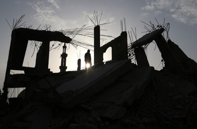 A Palestinian man walks atop the remains of a house that witnesses said was destroyed by Israeli shelling during a 50-day war last summer, in the southern Gaza Strip, March 10 (photo credit: REUTERS)